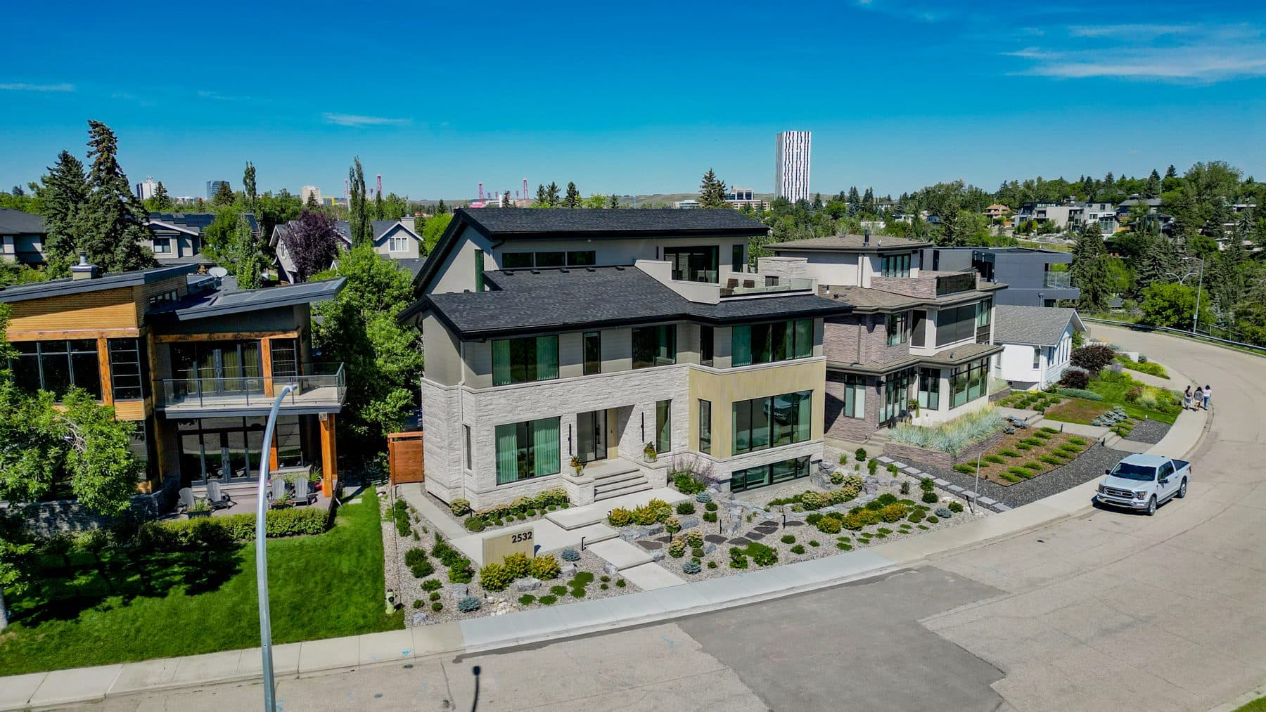 Aerial view along an inner-city Calgary street of established houses and mature trees.
