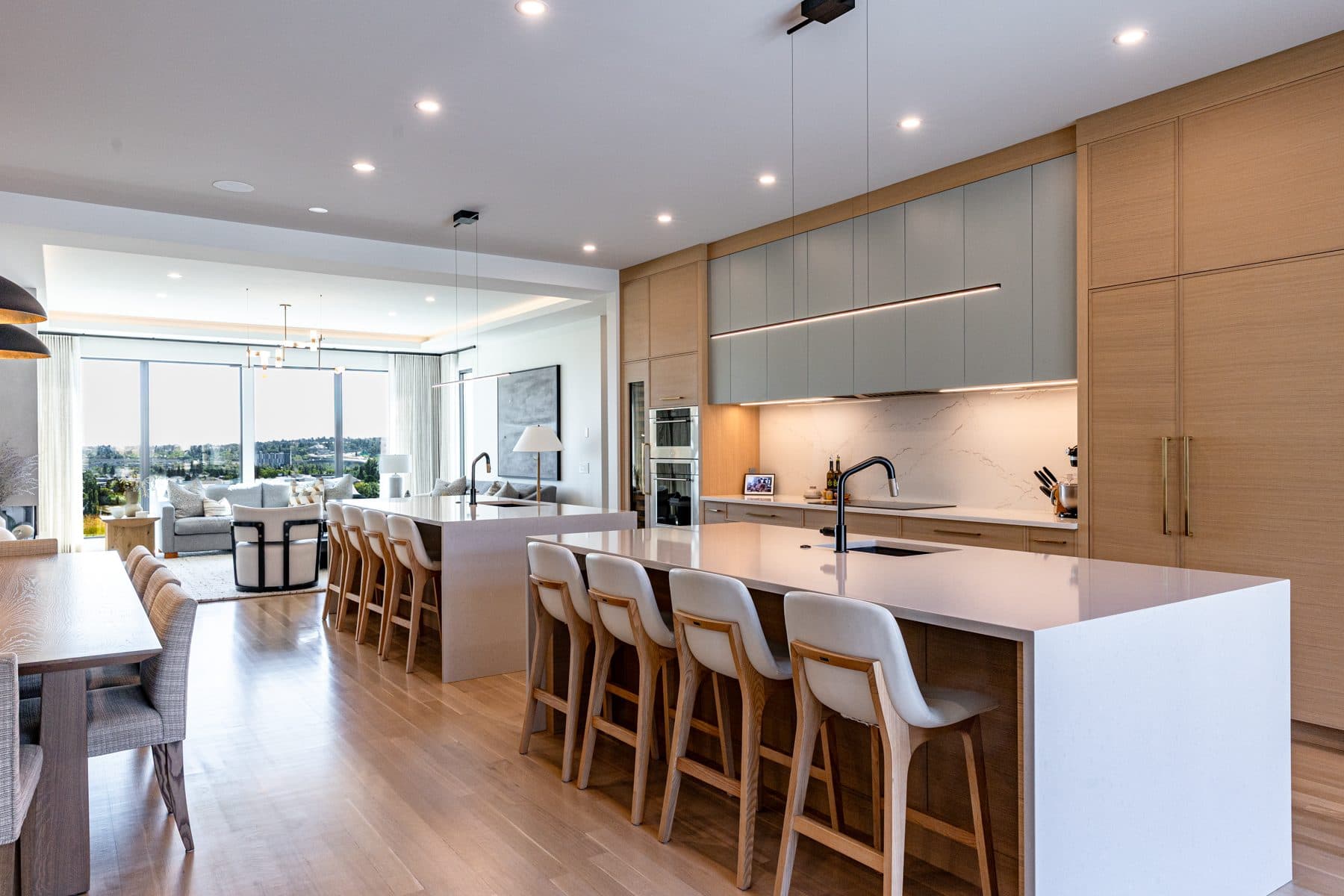 A kitchen with a waterfall stone island, rift oak cabinetry and a full-height range wall.