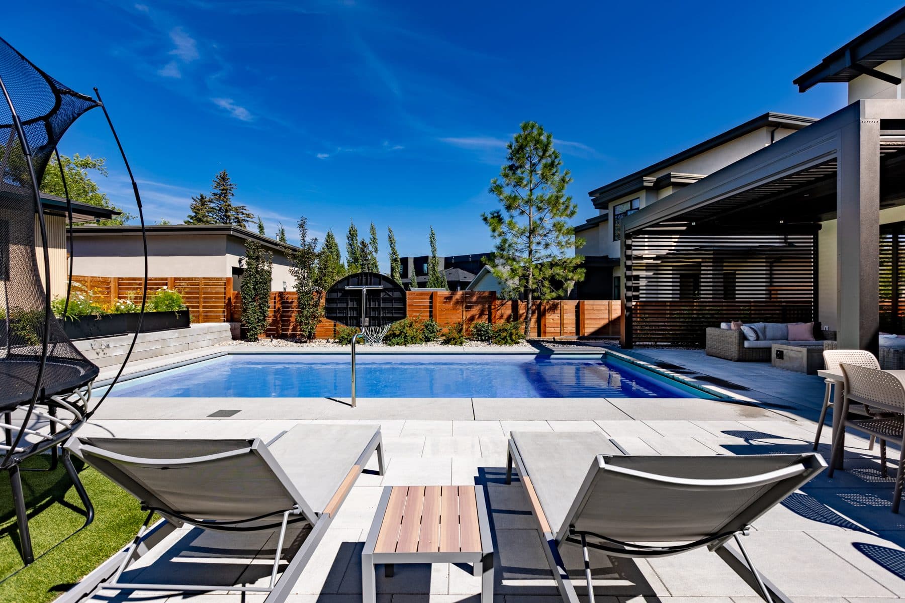 Loungers on a stone pool terrace, looking back toward the covered patio.