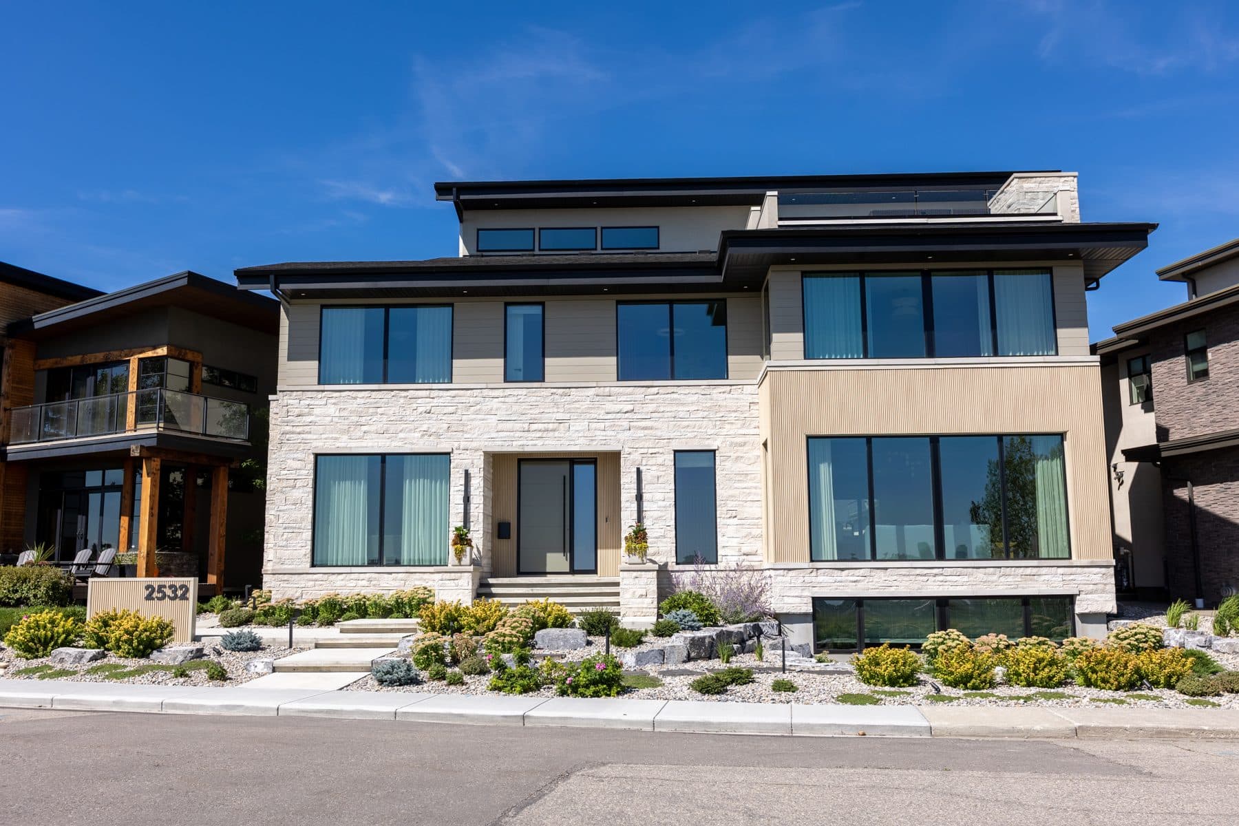 The front elevation of 2532 Toronto Crescent, a flat-roofed contemporary house in brick and dark metal on a corner lot.