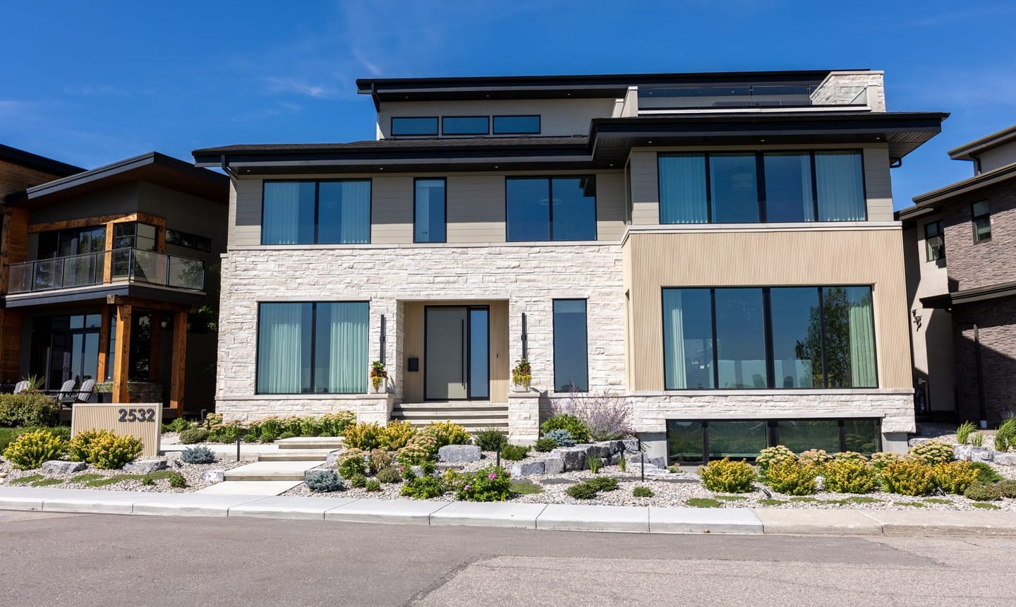 The front elevation of 2532 Toronto Crescent, a flat-roofed contemporary house in brick and dark metal on a corner lot.