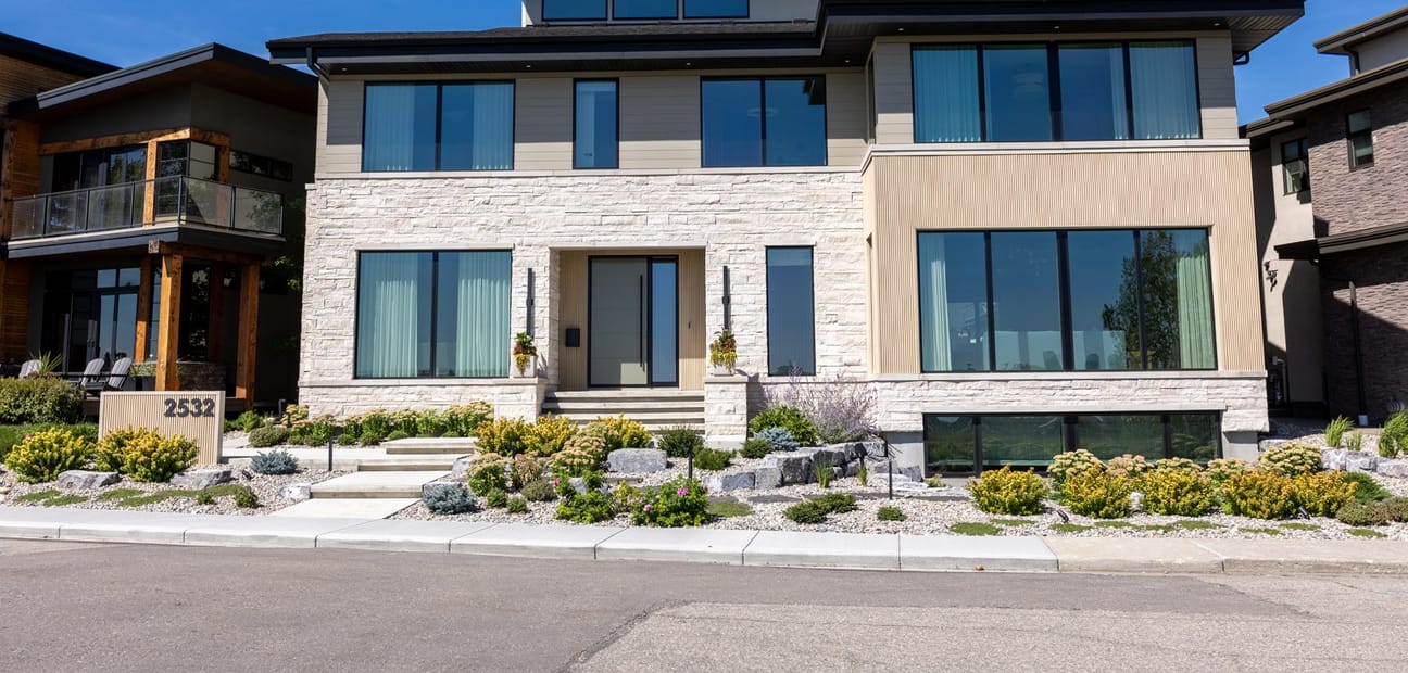 The front elevation of 2532 Toronto Crescent, a flat-roofed contemporary house in brick and dark metal on a corner lot.